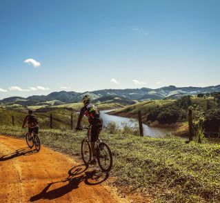 Two cyclists riding on a dirt trail with stunning mountain views and clear skies.